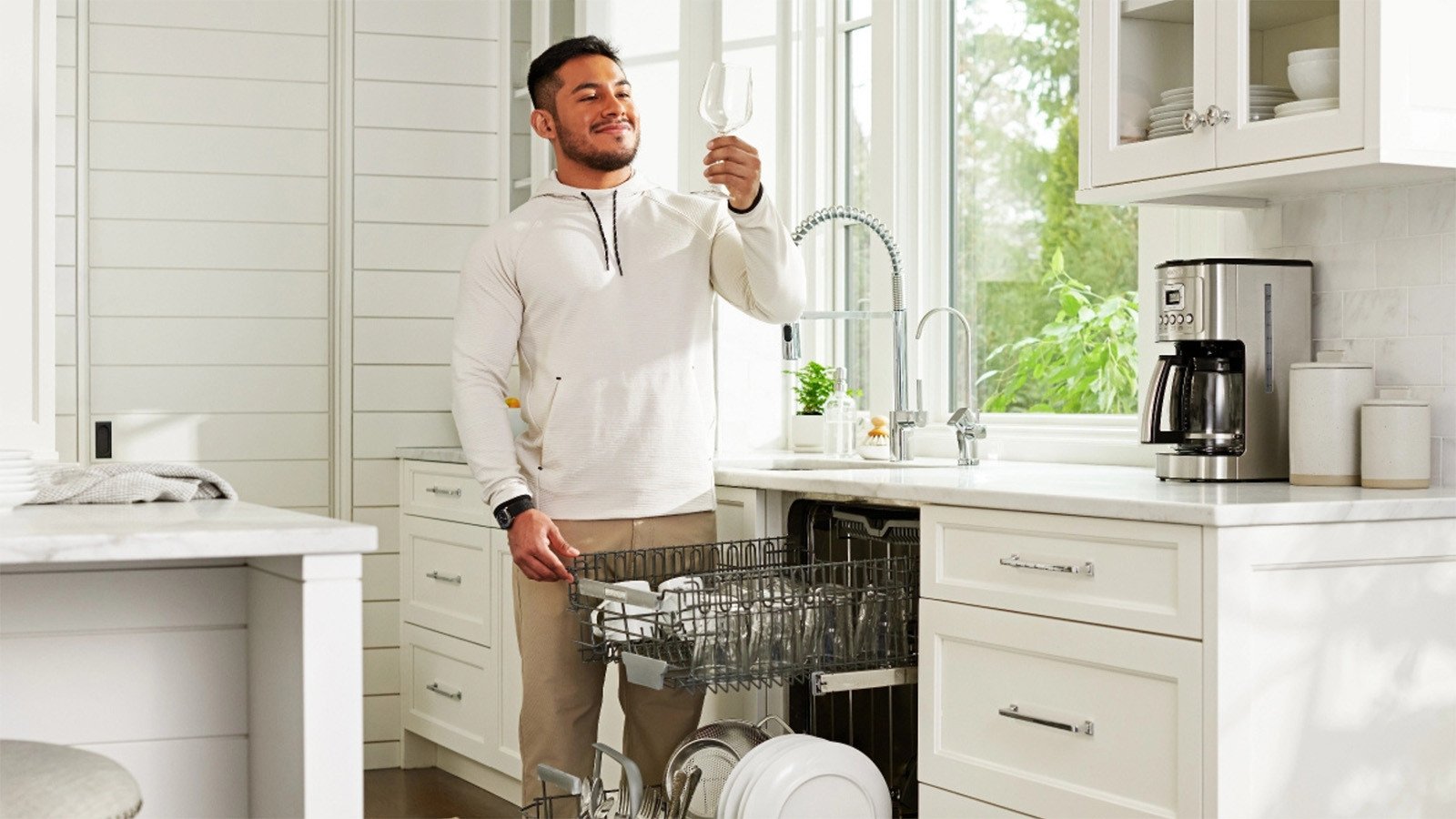 Person inspecting freshly cleaned glassware from dishwasher