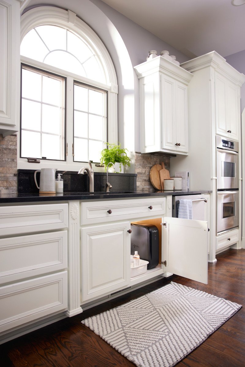 Open cupboard door with Culligan Tankless RO visible in modern kitchen