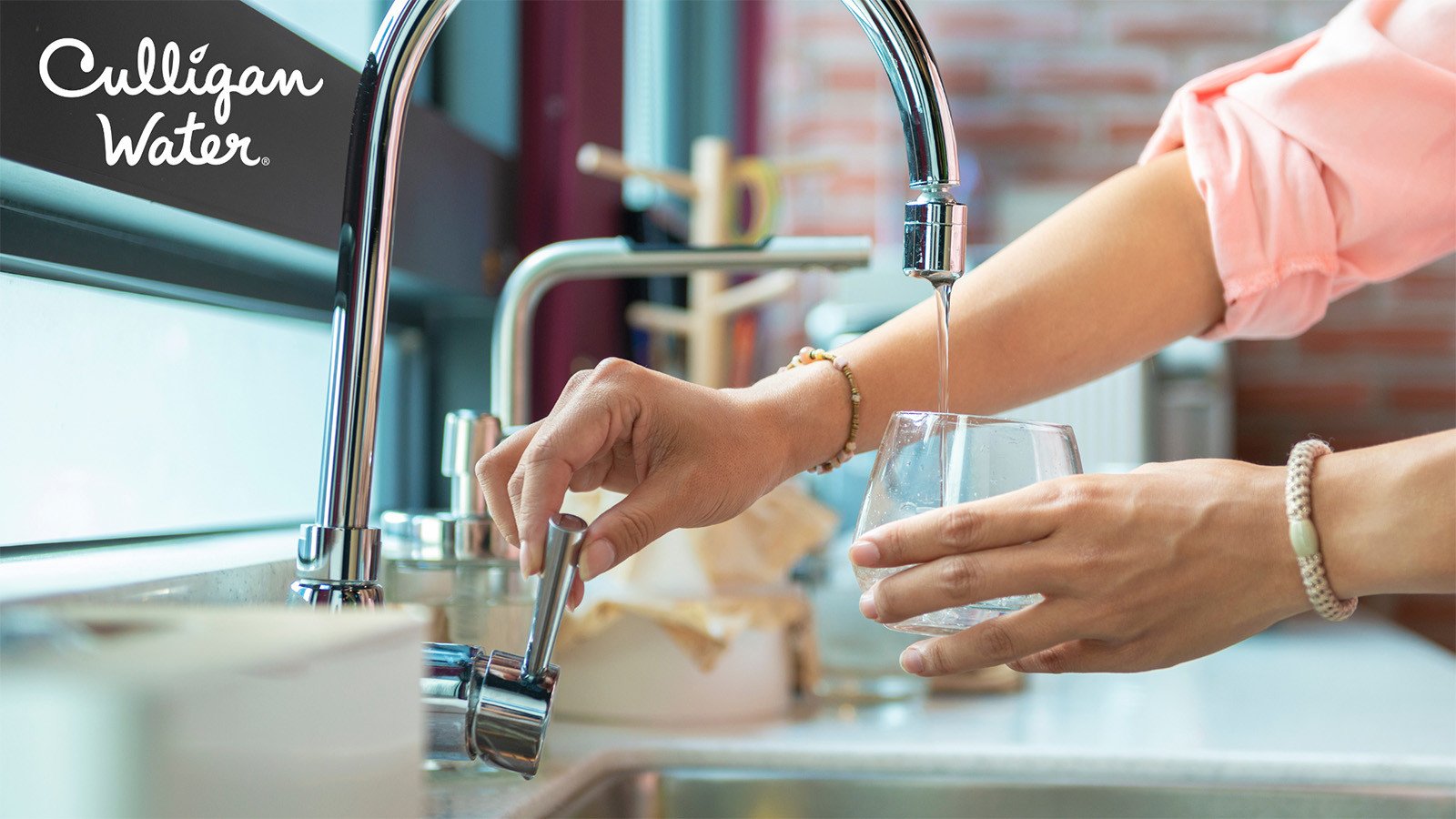 Person filling glass with water at faucet