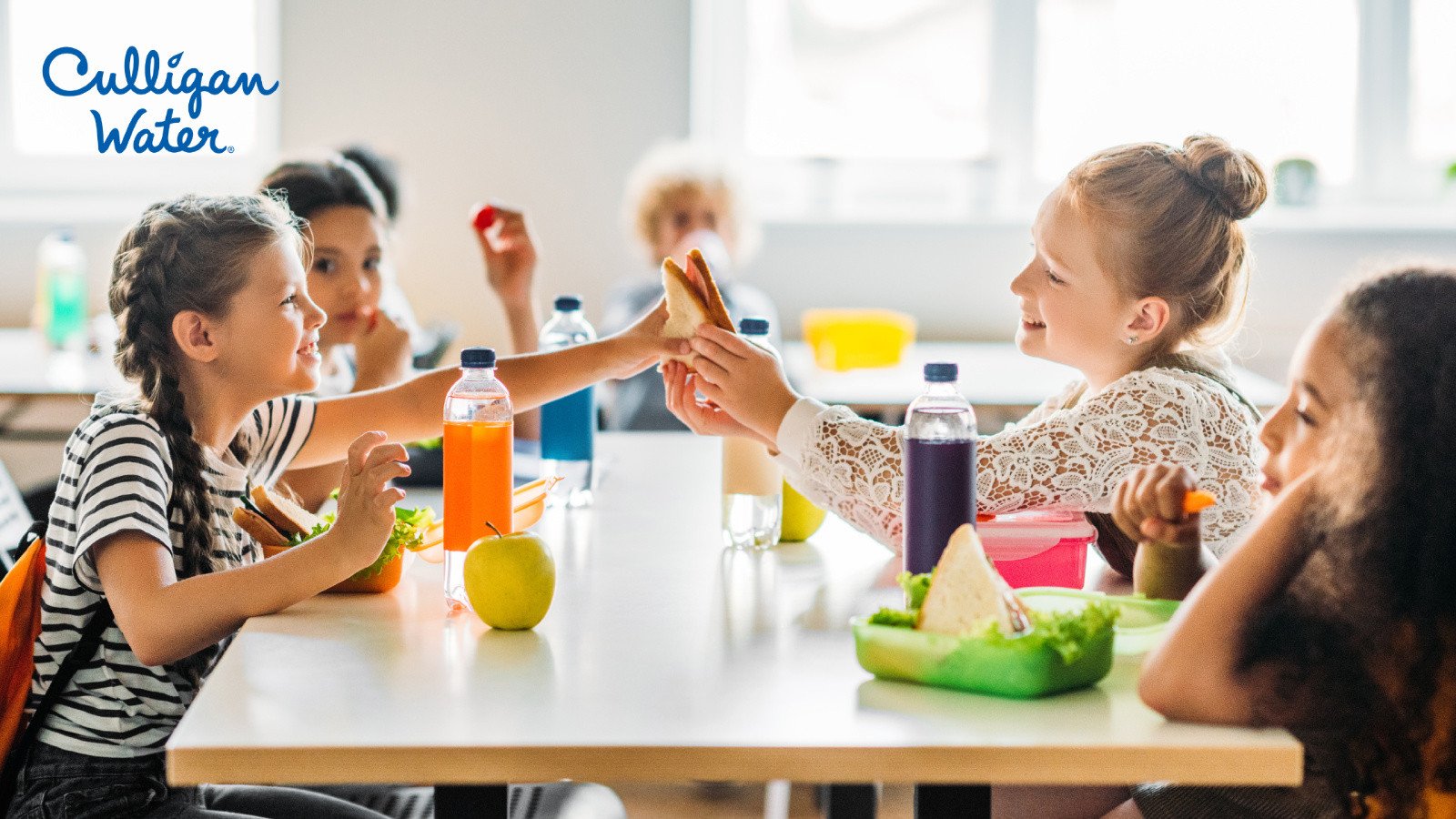 Kids sitting a lunch table sharing food